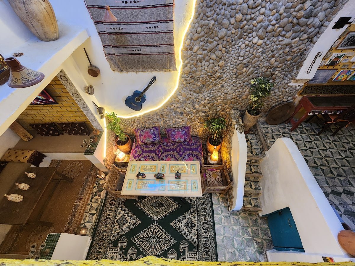 Dar Lala Chafia courtyard with natural stone walls, Moroccan seating, plants and patterned tiles